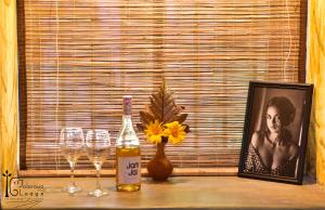 - une table avec des verres, une photo et une bouteille de vin dans l'établissement Galarawa Lodge, à Belihuloya