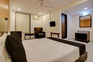a bedroom with a bed and a desk and a chair at Super OYO Flagship Hotel Golden Nest in Saravli