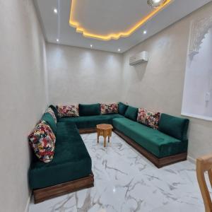 Bel appartement de 2 chambres في مراكش: غرفة معيشة مع أريكة خضراء وطاولة