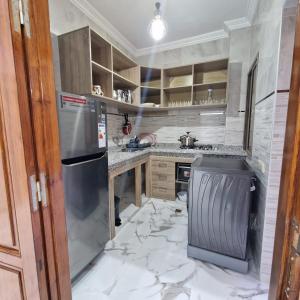 Bel appartement de 2 chambres في مراكش: مطبخ مع أرضية من الرخام مع ثلاجة