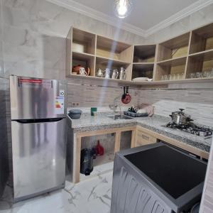 Bel appartement de 2 chambres في مراكش: مطبخ مع ثلاجة حديد مقاول للصدأ وخزانة