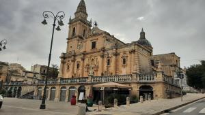 un antiguo edificio con una torre de reloj en una calle en Pura Vida Barocca en Ragusa