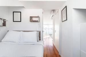 sypialnia z białymi ścianami i łóżkiem z białymi poduszkami w obiekcie Lisbon Skyline Terrace w Lizbonie