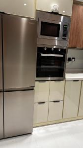 利雅德的住宿－Urban Bunks - Riyadh，厨房配有不锈钢冰箱和微波炉。