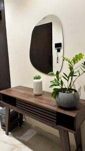 a mirror and two plants on a wooden table at Urban Bunks - Riyadh in Riyadh