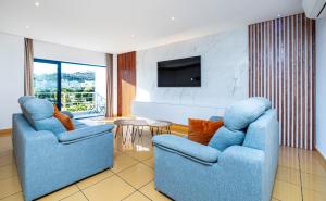 - un salon avec 2 chaises bleues et une télévision dans l'établissement Apartamento Orada HotTub Billiard & Pool view, à Albufeira