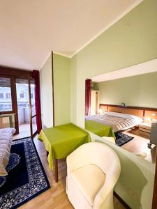 Habitación con 2 camas y una silla. en Hotel Battaglia en Battaglia Terme