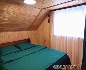 a bed in a wooden room with a window at Cottage Panorama Karpat in Volosyanka