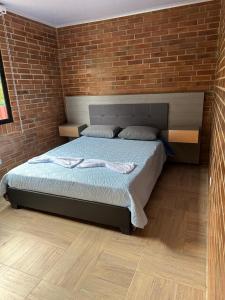 1 dormitorio con 1 cama con pared de ladrillo en Finca La Primavera - Cabañas Campestres de Descanso, en Sasaima