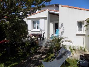 una pequeña casa blanca con una mesa en el patio en Saint Georges de Didonne - PETITE MAISON avec son petit coin de paradis extérieur en Saint-Georges-de-Didonne