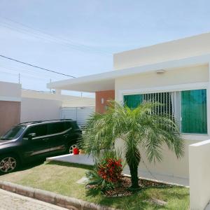 a car parked in front of a house with a palm tree at Casa com Piscina perto da praia in Salvador