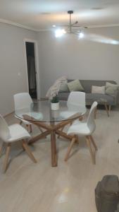 sala de estar con mesa de cristal y sillas blancas en Casa Tower en Vigo