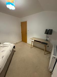 a bedroom with a bed and a table and a tv at 23 Lochburn Gardens - Carz in Maryhill