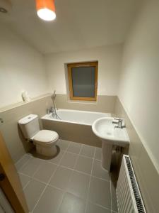 a bathroom with a toilet and a tub and a sink at 23 Lochburn Gardens - Carz in Maryhill