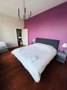 1 dormitorio con cama blanca y pared rosa en Gîte de groupe à la Ferme de Verdun, 1H30 de Paris, en Le Héron