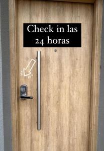 ein Schild an einer Tür, das den Check-in liest, hat Öffnungszeiten in der Unterkunft Apartamentos El Fortín in San Salvador de Jujuy