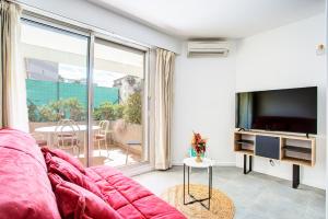 uma sala de estar com um sofá e uma televisão de ecrã plano em Appartement T2 moderne avec terrasse clim parking et wifi - 4ALB3 em Perpignan
