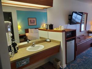 a bathroom with a sink and a mirror and a bed at Omak Inn in Omak