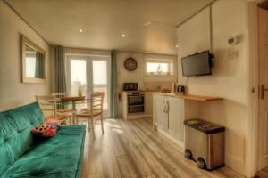 a living room with a green couch and a kitchen at Stunning Solent View Beachfront Apartment, Sleeps4 in South Hayling