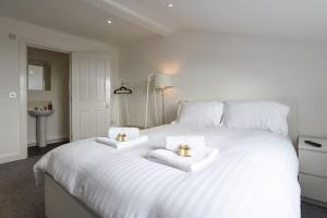 a white bed with two towels and two candles on it at Spacious 2 Bedroom Flat with Parking in Portsmouth