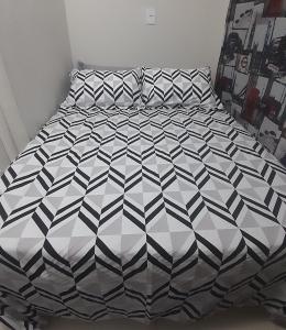 a bed with a black and white comforter at Hostel bons sonhos Um Quarto uma Cama de Casal in Penha