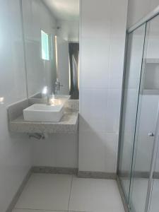 a white bathroom with a sink and a mirror at Hotel Treviso in Linhares