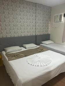 two twin beds in a room with avertisement at Hotel Treviso in Linhares
