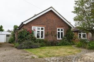 a brick house with white windows and a driveway at Cosy One Bed Bungalow Style Annex in Southbourne