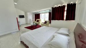 a white bedroom with a bed and a living room at Sunshine Villa Mauritius in Flic-en-Flac