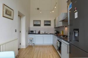 a kitchen with white cabinets and a wooden floor at Naval Officers Quarters Flat in Gosport