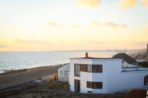 a house on the beach with the ocean in the background at Amazing view High end beachfront 3BR 5beds 7 guest in South Hayling