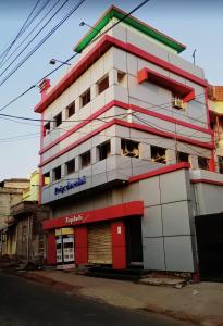 un grand bâtiment blanc avec des garnitures rouges dans l'établissement Hotel Priyadarsini, à Bānkura