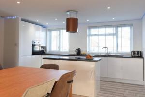 a kitchen with white cabinets and a wooden table at Amazing view High end beachfront 3BR 5beds 7 guest in South Hayling