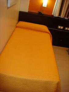 Bett in einem Zimmer mit orangefarbener Tagesdecke in der Unterkunft Hotel León Tierra de Vinos in La Palma del Condado