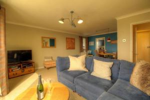 a living room with a blue couch and a tv at Modern 2BR w sea views beach access in South Hayling