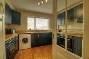 a kitchen with blue cabinets and a washer and dryer at Modern 2BR w sea views beach access in South Hayling