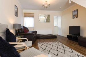 a living room with leather furniture and a flat screen tv at Centrally Located 3Bed Family Home in Portsmouth