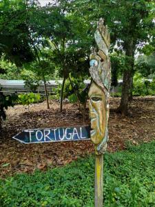 a wooden sign with a statue of a face on it at Tortugal Boutique River Lodge in Rio Dulce