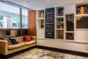 a lobby with a couch and a sign on the wall at Xtay Privilege Botafogo - Apartamentos a 6min da praia e próximo a Copacabana in Rio de Janeiro