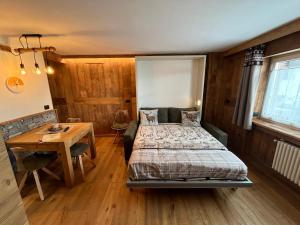 een slaapkamer met een bed, een tafel en een bureau bij Maison Meynet Mountain Charm in Breuil-Cervinia