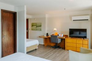 a hotel room with a bed and a desk with a television at Xtay Privillege Botafogo in Rio de Janeiro