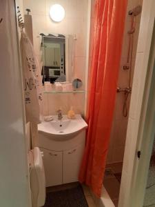 a bathroom with an orange shower curtain and a sink at Szoba kilátással apartman in Gárdony