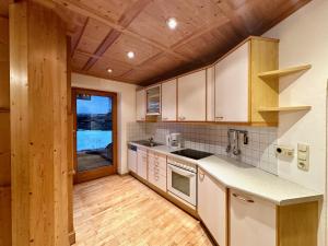 Il comprend une cuisine avec des appareils blancs et un plafond en bois. dans l'établissement Apartments Max & Moritz, à Kirchberg in Tirol