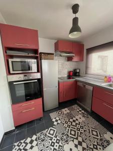 a kitchen with red cabinets and a tile floor at Le Duplex Paris Basilique Stade de France in Saint-Denis