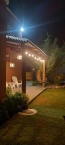 a pergola with two white chairs under it at night at El Bagual de Monte XL in San Miguel del Monte