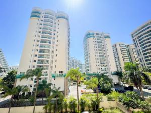 里約熱內盧的住宿－Lobie Barra da Tijuca Mundo Novo，两座高大的白色建筑,在有棕榈树的城市