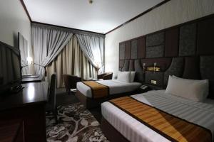 ドバイにあるKnight Armour Hotelのベッド2台とデスクが備わるホテルルームです。