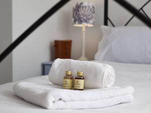 two bottles of essential oils sitting on a towel on a bed at Large Family Home Private Garden Beach 2 mins Walk in South Hayling