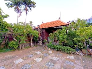 a house with a courtyard with palm trees and a building at Sajjana House Bali By Magno in Nusa Dua