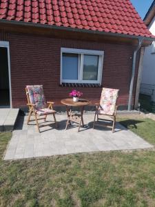 two chairs and a table in front of a house at Ferienwohnung Feldblick in Upahl